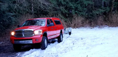 Red truck pulling trailer in snow