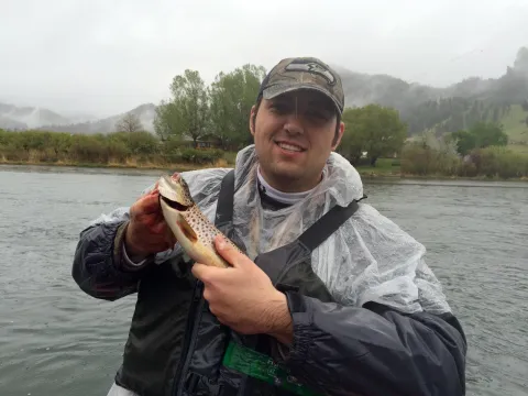 Man holding trout in the rain.