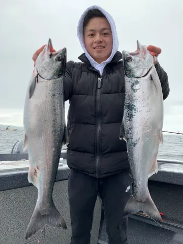 holding two coho.